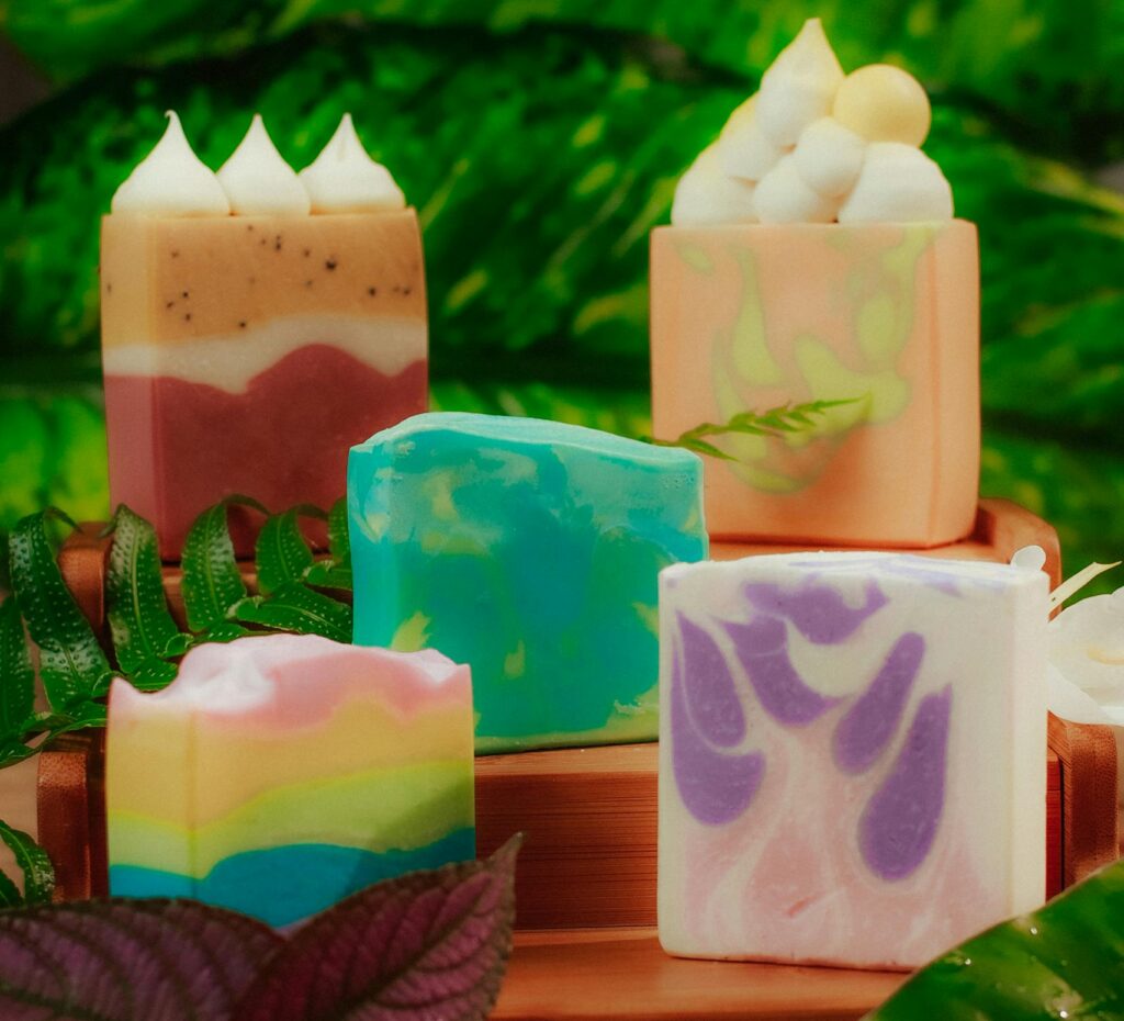 Vibrant handcrafted soap bars on a wooden tray with tropical leaves, perfect for beauty products.