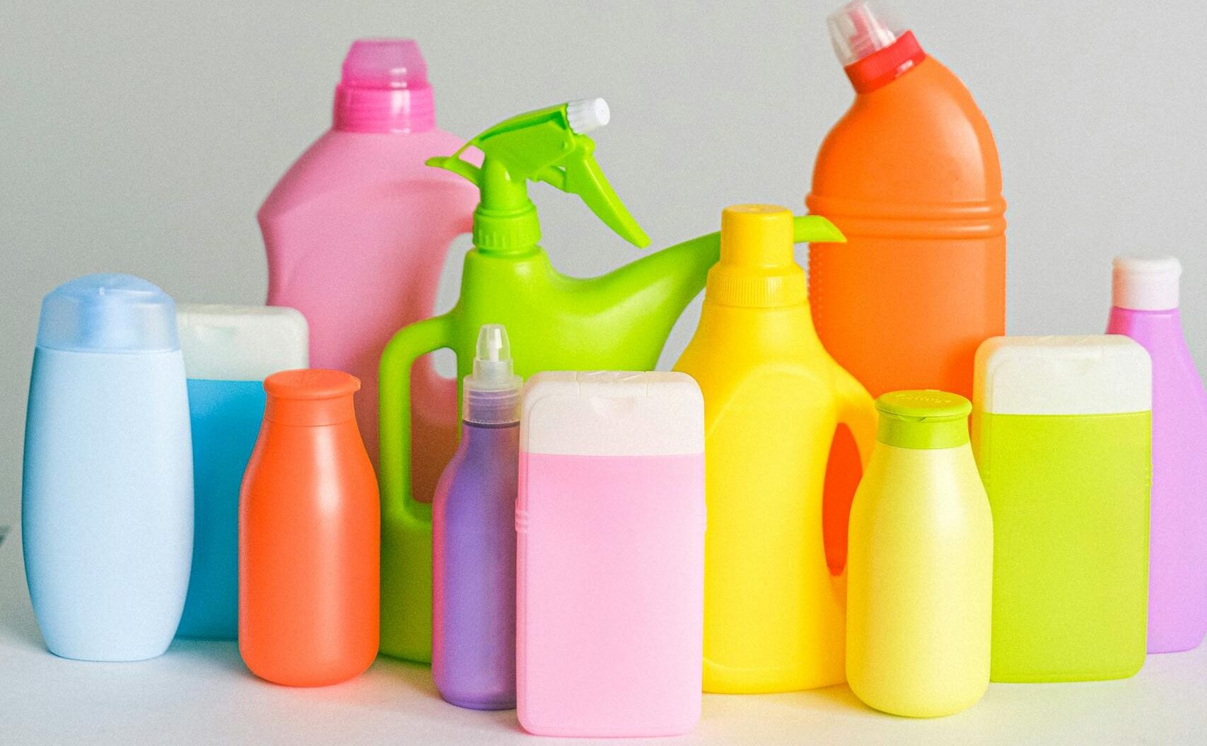 Assorted colorful plastic cleaning bottles on a white background.