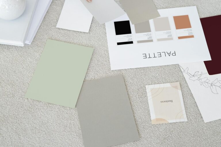 Designer sits on carpet with color palettes and samples, planning creative project.