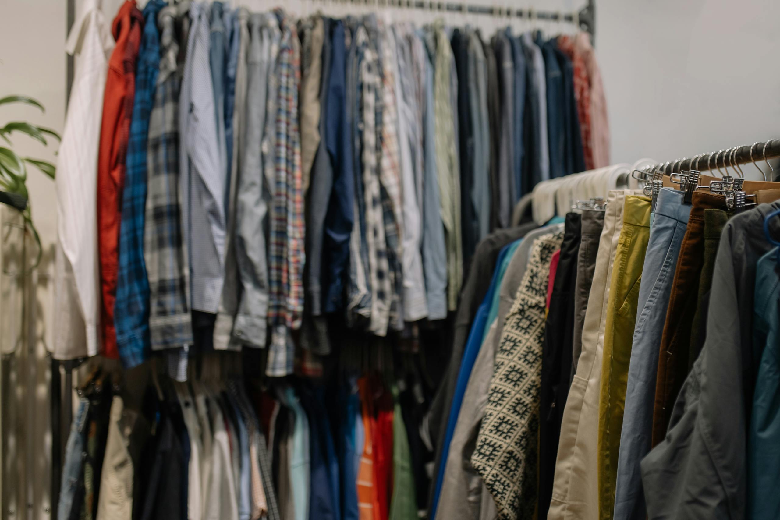 Assorted clothing on racks in a thrift shop, showcasing various styles and colors.